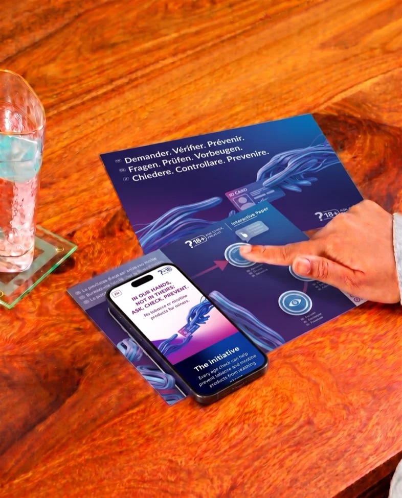 The interactive paper and a phone showing the campaign page, on a shop counter